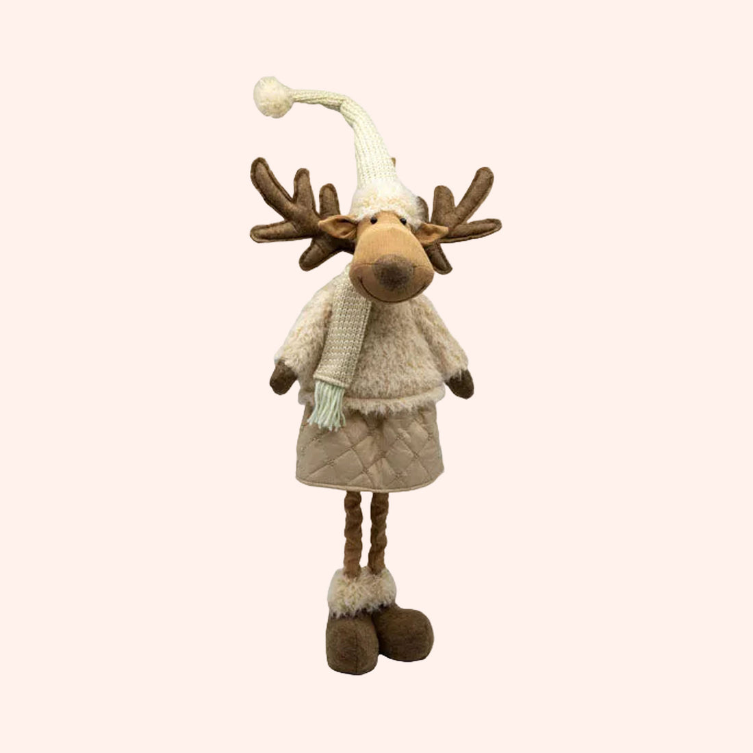 A plush moose decoration wearing a cream knit hat with a pom-pom, a cream sweater, a quilted beige skirt, and brown antlers, photographed on a plain background.